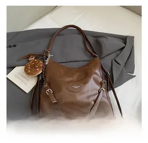 Detailed shot of a brown vintage Hobo bag on a grey blazer with a cute donut charm