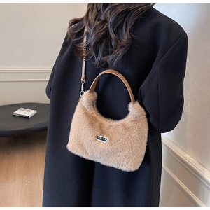 Détail du sac à main en peluche beige avec bandoulière en cuir brun et logo en métal