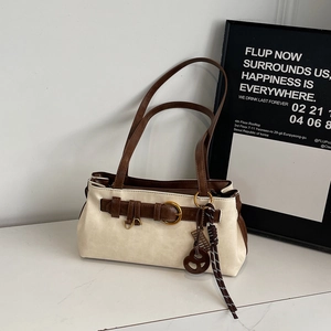 Détail du sac sous les bras bicolore avec boucle dorée et pendentif en forme de cœur
