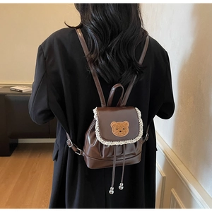 Close-up of brown PU leather mini backpack with lace trim and bear embroidery detail