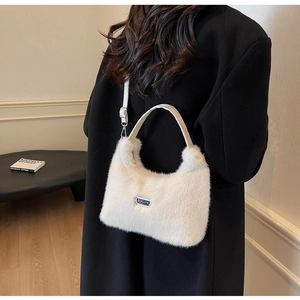 Détail du sac à main en fausse fourrure blanche douce avec plaque logo sur manteau noir