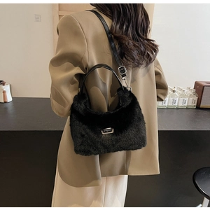 Détail du sac à main en peluche noire avec plaque logo argentée et bandoulières en cuir