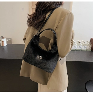 Détail du sac à bandoulière en fausse fourrure noire avec logo et sangle en cuir