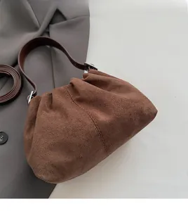 Detail view of brown suede pleated hobo bag featuring smooth handles and long shoulder strap