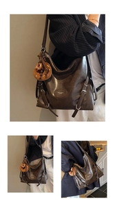 Detail view of large dark brown leather tote bag with adjustable straps and plush donut charm