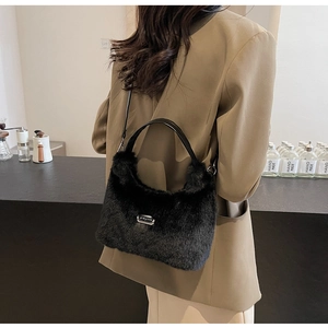 Détail du sac à bandoulière en fausse fourrure noire avec logo argenté et cuir