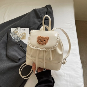 Close-up of cream PU mini backpack featuring a plush bear patch and delicate lace trim