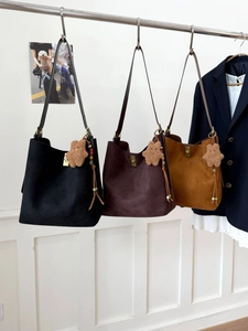 Three suede bucket bags in black, dark brown, and caramel with bear charms and gold locks