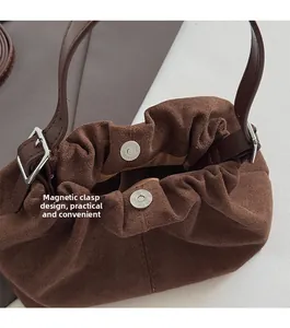 Detail of brown suede handbag featuring a practical magnetic closure and pleated edge