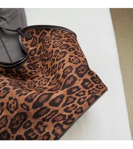 Close-up of leopard print tote bag fabric texture with premium brown leather trim details