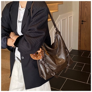 Detail of deep brown leather tote bag featuring silver hardware and a plush charm