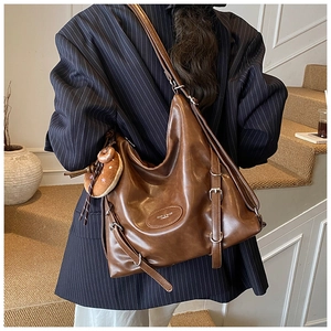 Detail of vintage brown leather tote bag with decorative buckle and plush charm