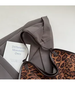 Close-up of leopard print tote bag with brown leather trim resting on grey suit jacket