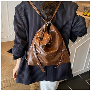 Close-up of brown vintage leather tote bag with silver buckle and donut plush charm