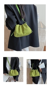 Detailed close-up of emerald green pleated suede cloud bag with minimalist shoulder strap