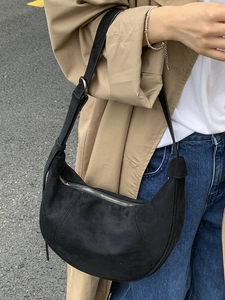 Moderna borsa hobo nera in pelle scamosciata da donna con un trench color kaki