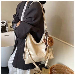Detail view of beige tote bag with embossed logo and decorative doughnut plush pendant