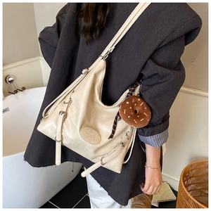 Detailed view of the large off-white tote bag with a decorative donut plush charm