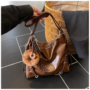 Detail of vintage brown tote bag featuring silver rings and donut plush pendant