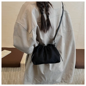 Detail view of the black drawstring crossbody bag showing the sleek leather texture and strap