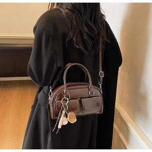 Detail view of a vintage dark brown leather boston bag with baseball charms and front pockets