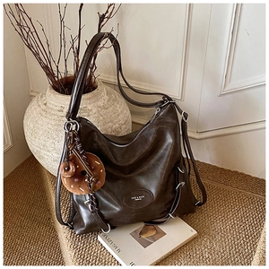 Detailed view of deep brown hobo bag with vintage leather texture and plush donut charm