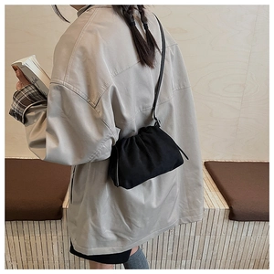 Close-up of black pleated drawstring cloud bag with soft fabric texture and slim shoulder strap