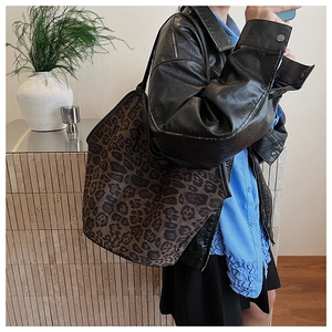 Detail shot of a large leopard print tote bag with a soft texture on a shoulder