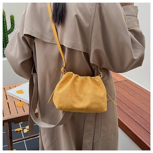 Detail view of ginger suede pleated cloud bag with slim shoulder strap worn by a model