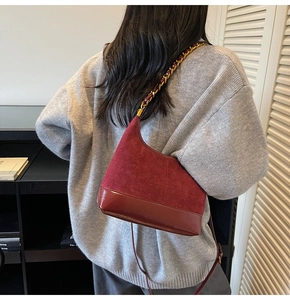 Detail of burgundy patchwork suede and leather shoulder bag with gold chain strap