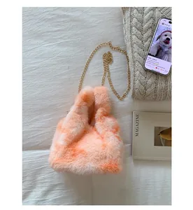 Detail of orange gradient faux fur handbag with golden chain on a cozy knit background