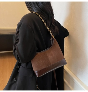 Detail view of the brown retro dumpling bag with metal chain strap on woman shoulder