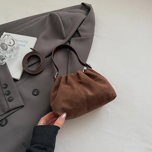 Detail of a brown suede pleated cloud bag with silver hardware and adjustable strap