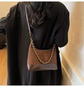 Detail of vintage brown suede and leather shoulder bag with gold chain on model
