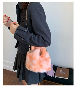 Detailed macro view of orange faux fur texture and gold chain strap on stylish handbag