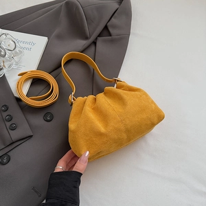 Detailed macro view of yellow suede pleated dumpling bag with silver metallic hardware
