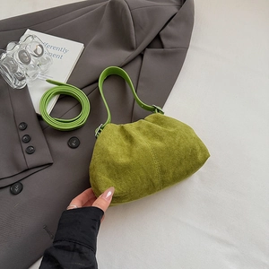 Detail of avocado green faux suede handbag featuring silver metal hardware and leather strap