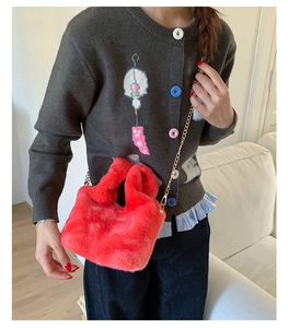 Chic red faux fur plush handbag with gold chain strap carried by a model on grey outfit