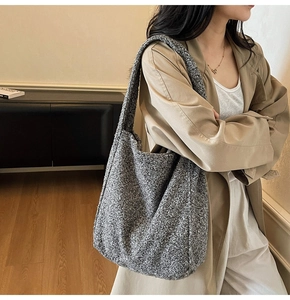 Détail de la texture en laine grise du grand sac fourre-tout porté sur un trench