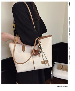 Detail view of large cream tote bag with brown trim and decorative bear charm