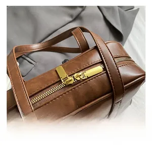 Detail von Doppelreißverschluss und mattgoldenen Metallteilen an der braunen Boston Bag