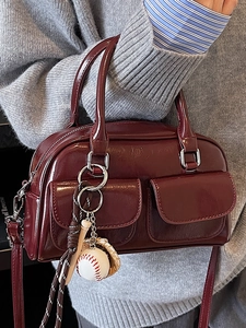 Burgundy faux leather Boston bag with baseball charm on a female model shoulder