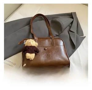 Detail der braunen Vintage-PU-Leder-Einkaufstasche mit Logo und süßem Bärenanhänger