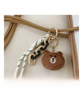 Detail view of a cute brown plush bear charm and bicolor chain on a tote bag