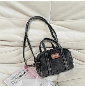 Detail of distressed black denim handbag with contrast stitching and leather label