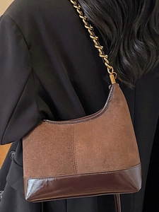 Vintage brown suede moon bag with gold chain strap shown on a model in a black suit