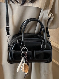 Elegant black patent leather Boston bag with double handles and a stylish pendant strap