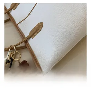 Detail of lychee pattern leather tote bag showing fine stitching and brown bear charm