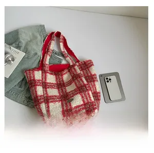 Detail view of the red and white checkered plush tote bag with a metallic logo plate