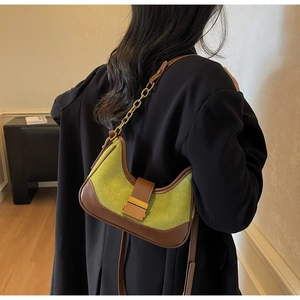 Detail of vintage baguette bag with green suede, brown leather and gold chain strap